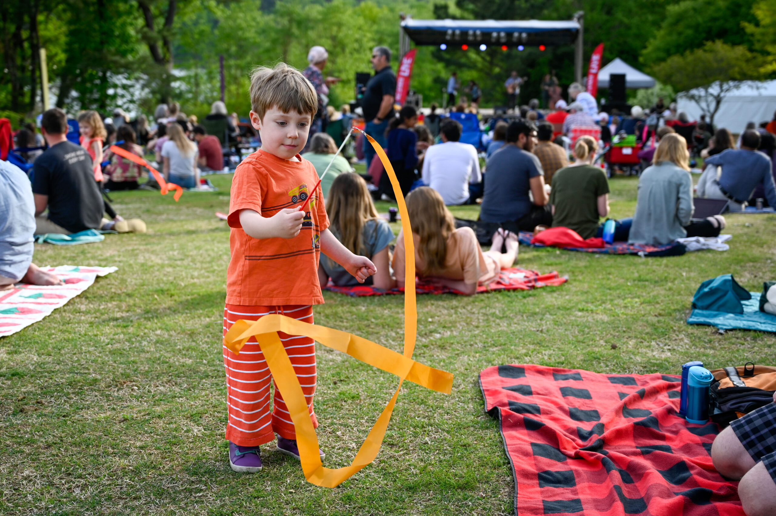 child in audience playing with ribbon at outdoor concert